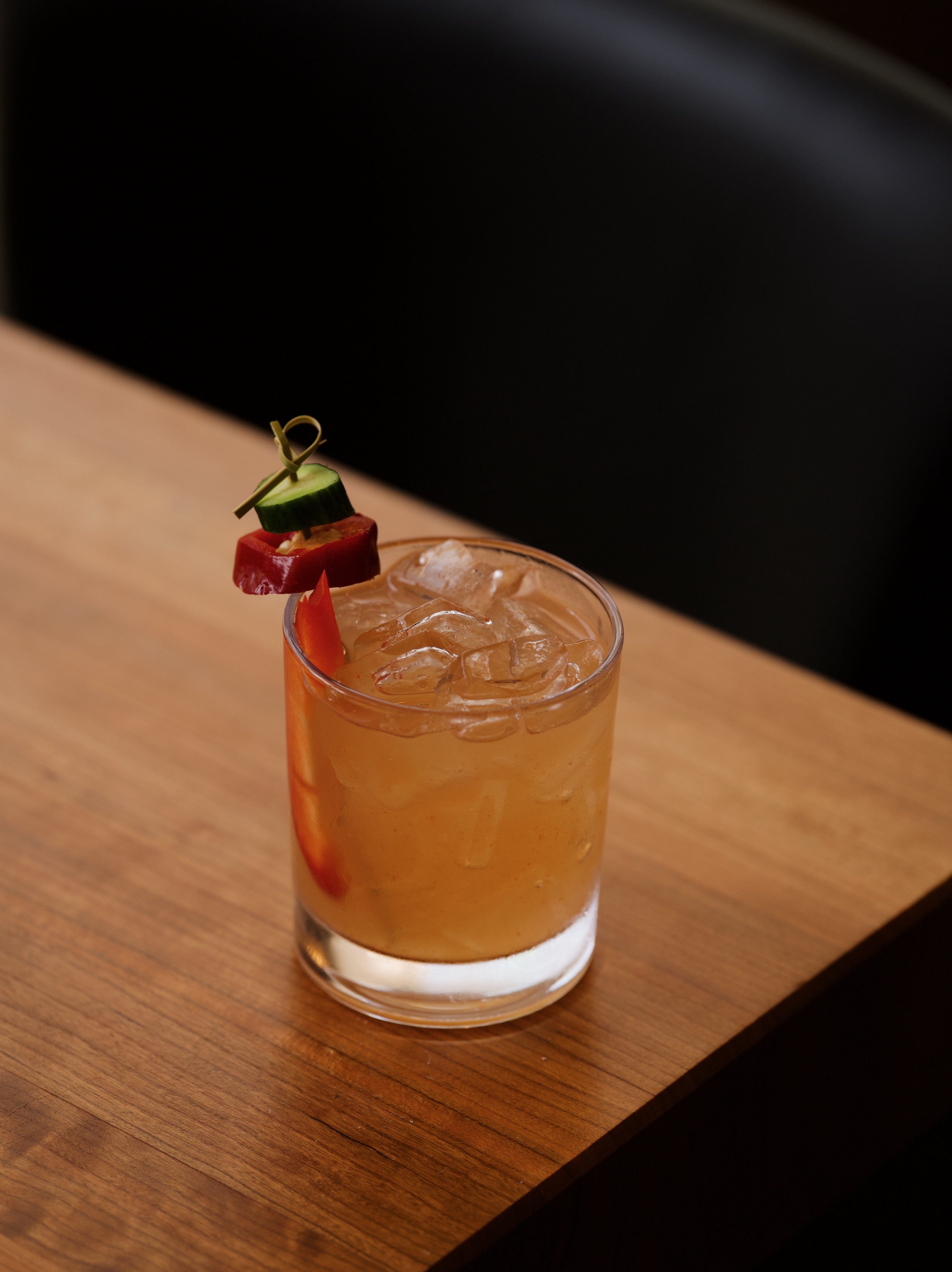 Craft whiskey cocktail with cucumber and chili garnish