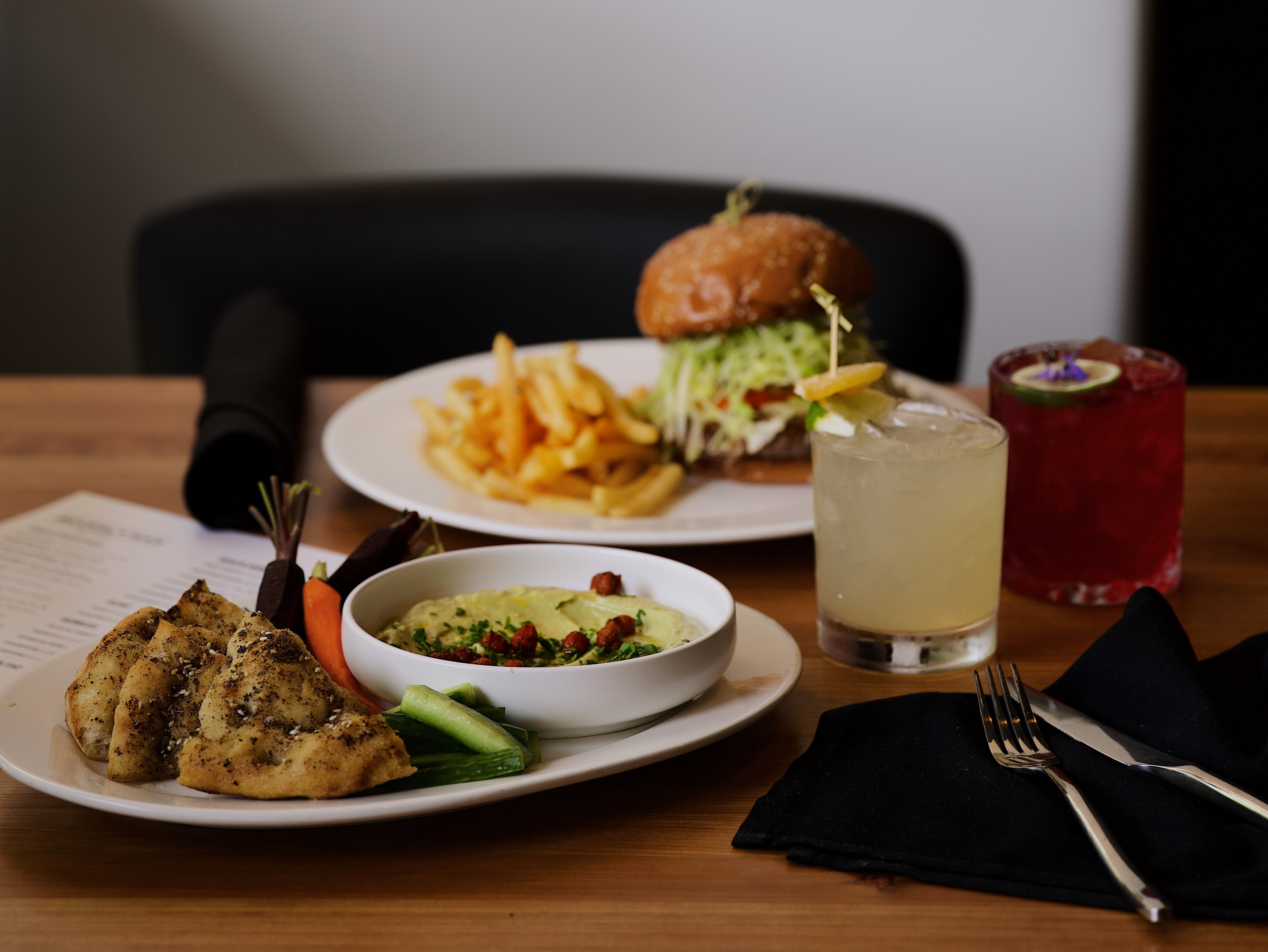 Beverly Bar table spread — burger, hummus, and craft cocktails